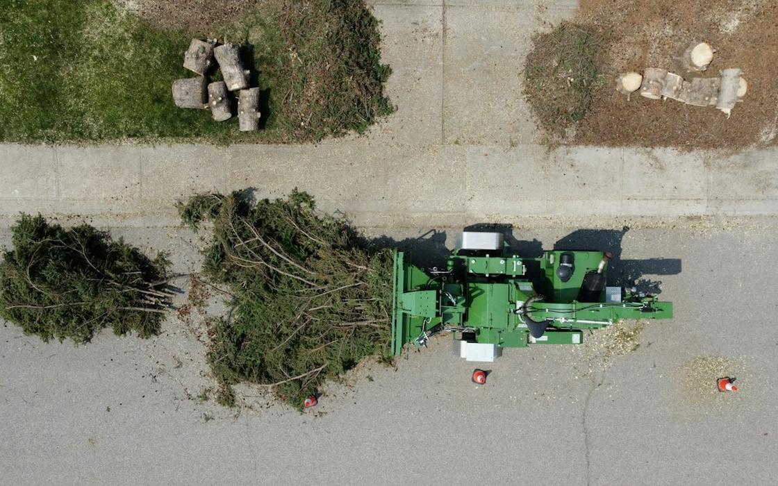 Crew feeding a pile of storm brush and branches into a wood chipper in Framingham, MA